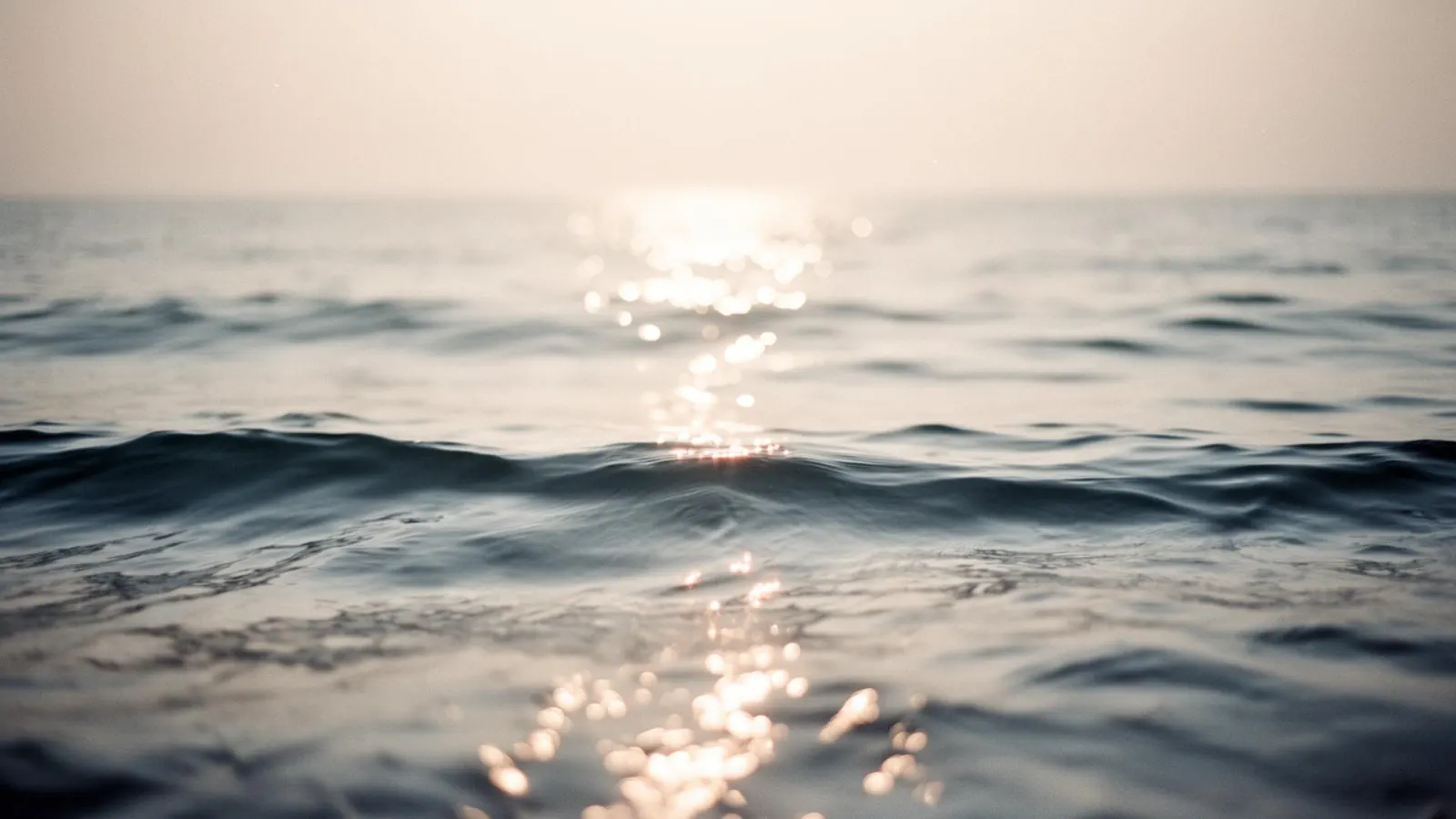 Soft bokeh light on quiet ocean waves at dawn
